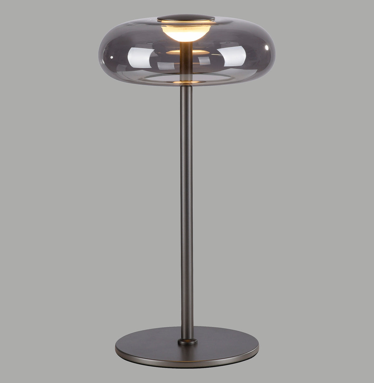 Lampe à poser de face sur fond gris, abat-jour ovale en verre fumé
