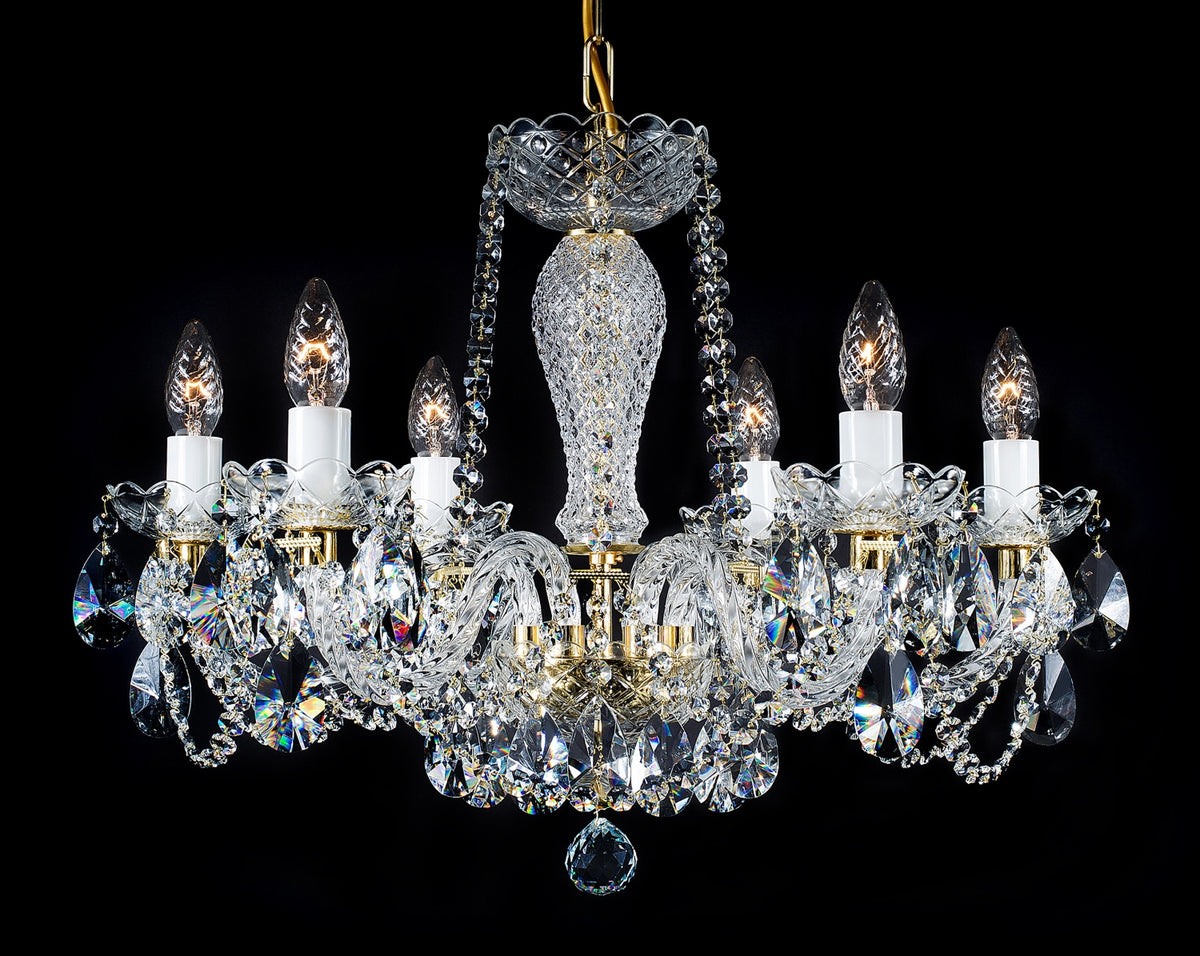Lustre en cristal doré à six bras, suspendu, sur fond noir.