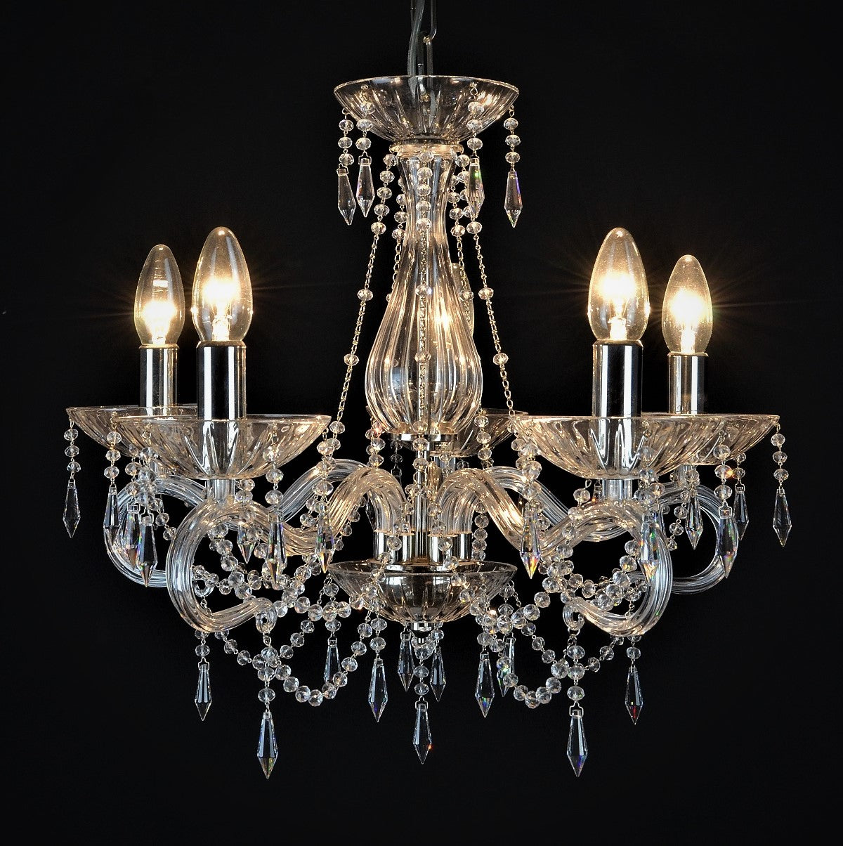 Lustre en cristal à six bras courbés, pampilles et ampoules allumées, vue de face sur fond noir