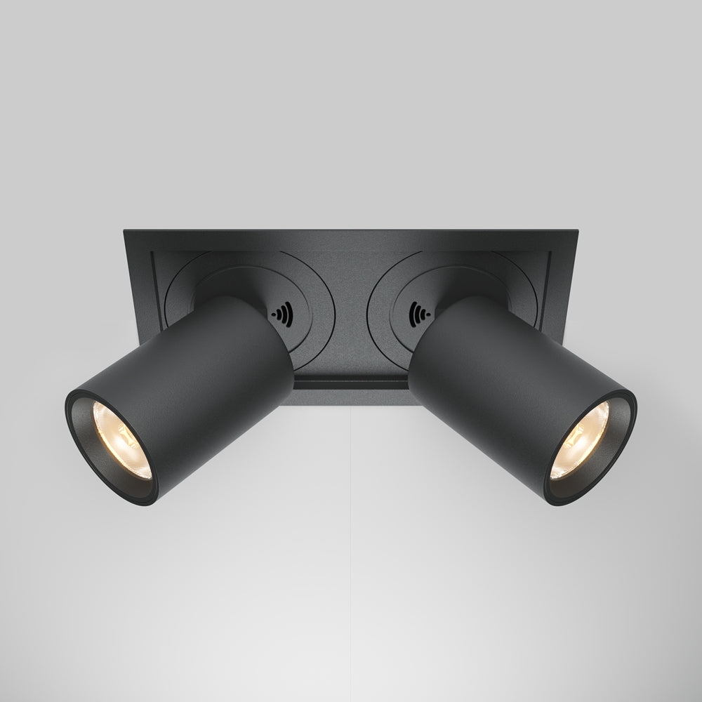 Spot encastré noir à deux têtes cylindriques orientables, vu de dessous au plafond.