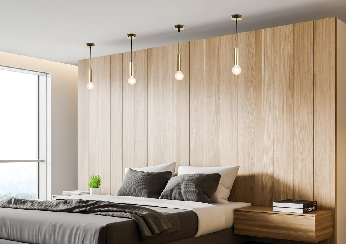 Mise en ambiance chambre avec quatre suspensions dorées alignées devant une tête de lit en bois