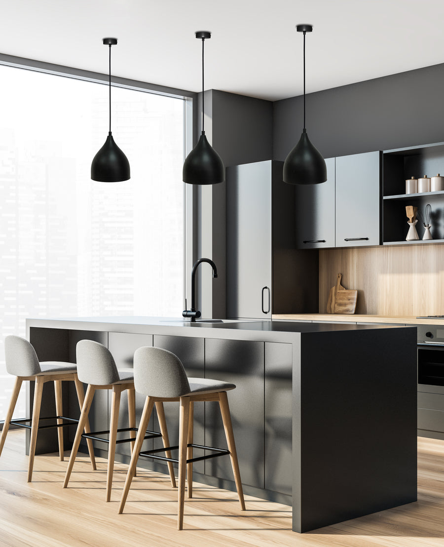 Vue d'ensemble d'un coin repas éclairé par trois luminaires suspendus noirs