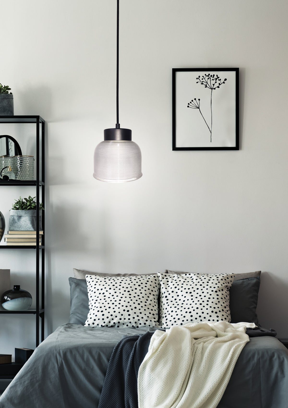 Suspension allumée au-dessus d'un lit, ambiance chambre contemporaine avec étagère et cadre.