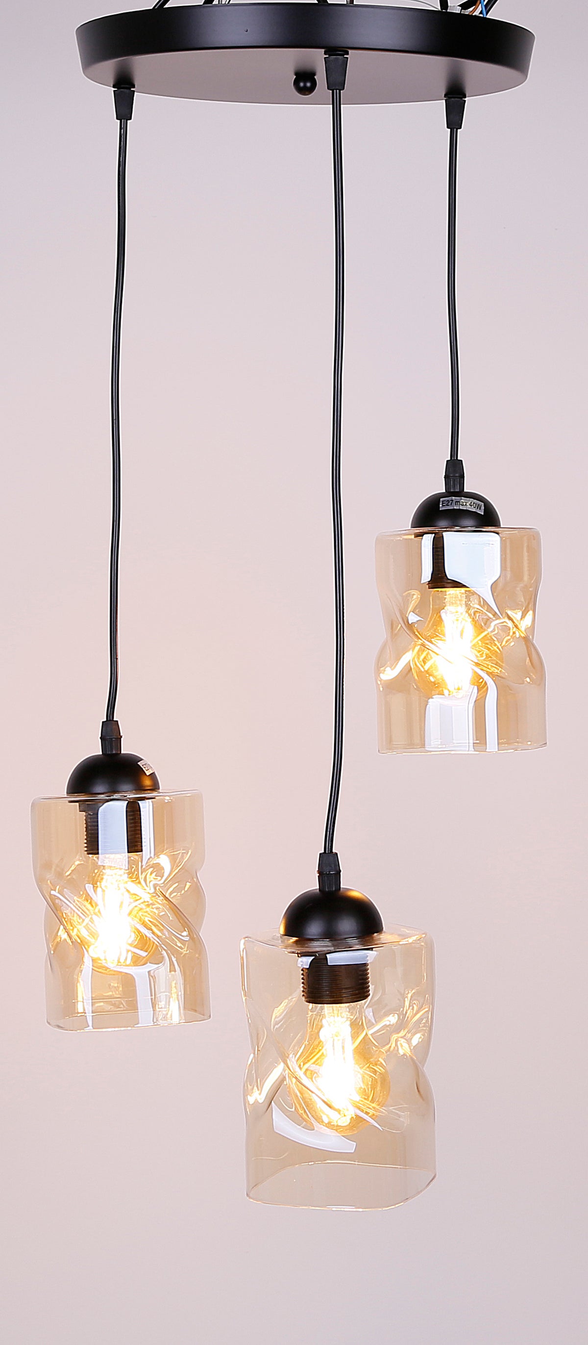 Luminaire allumé sur fond beige clair, ampoules visibles dans verres ambrés
