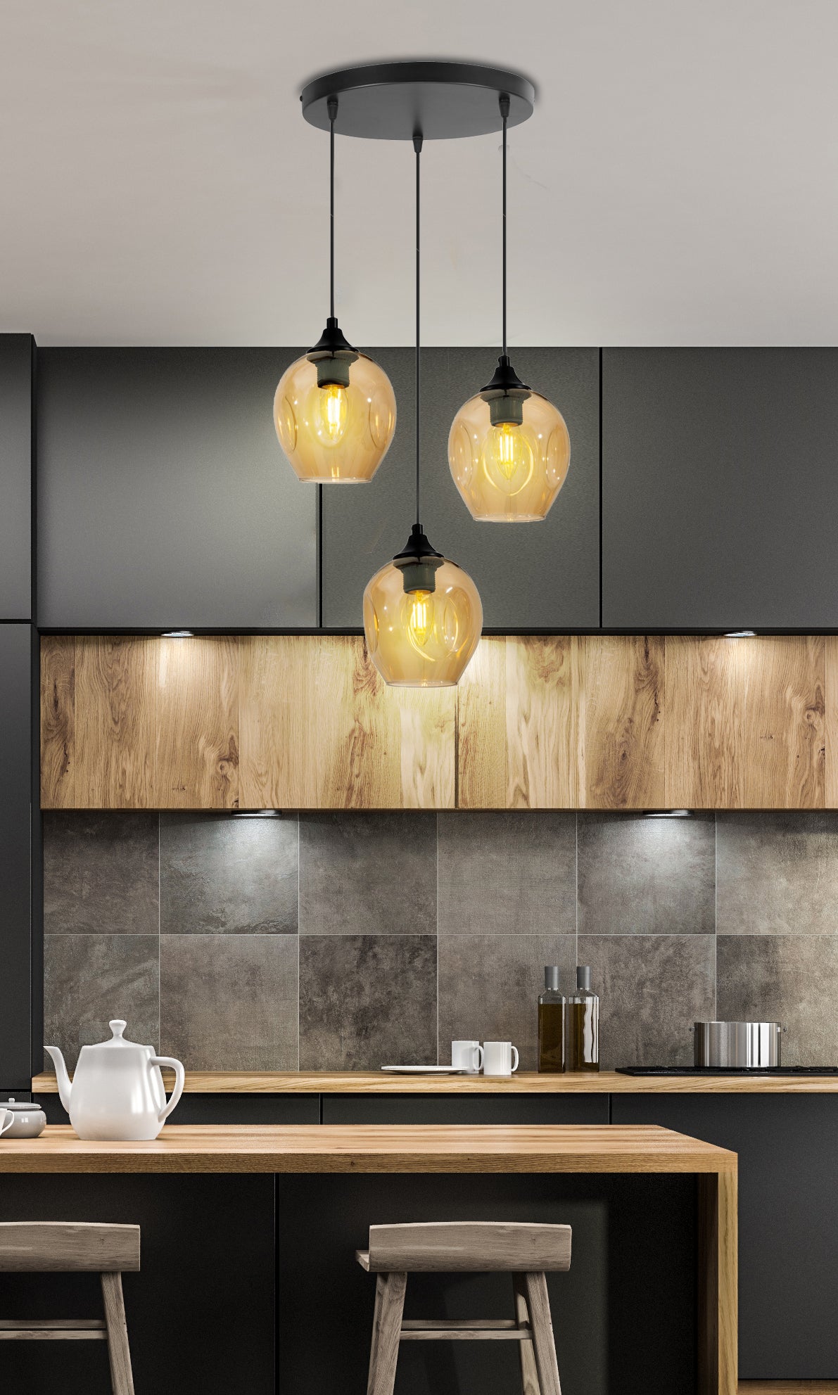Mise en ambiance cuisine moderne, suspension allumée au-dessus d'un îlot central en bois.