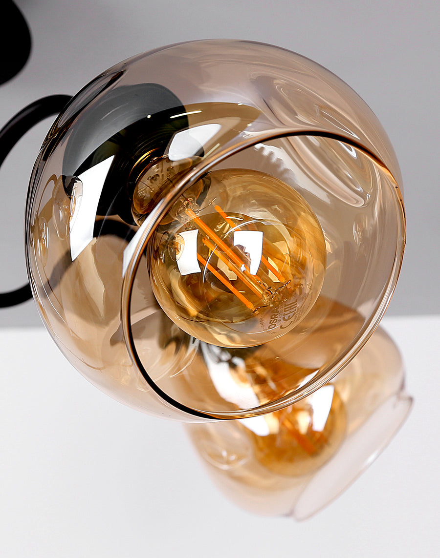 Détail rapproché d'une sphère en verre ambré et de l'ampoule à filament
