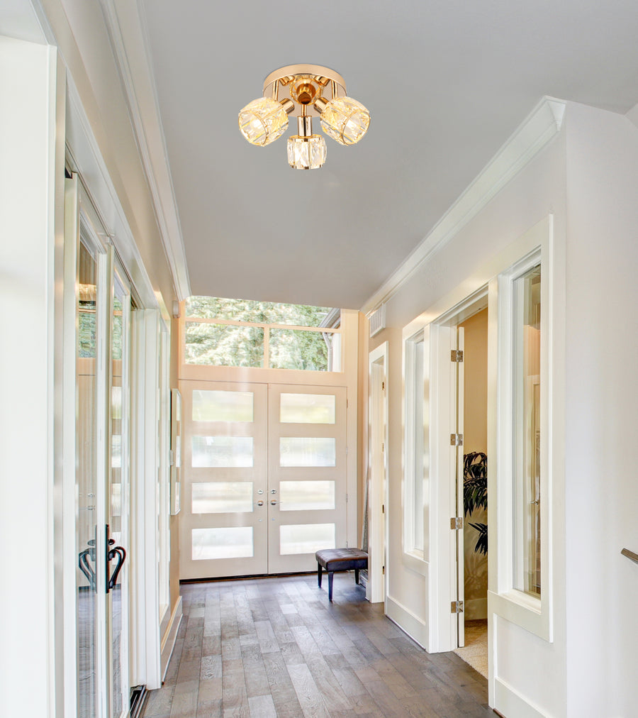 Luminaire doré installé au plafond dans un couloir blanc, avec portes vitrées et parquet.