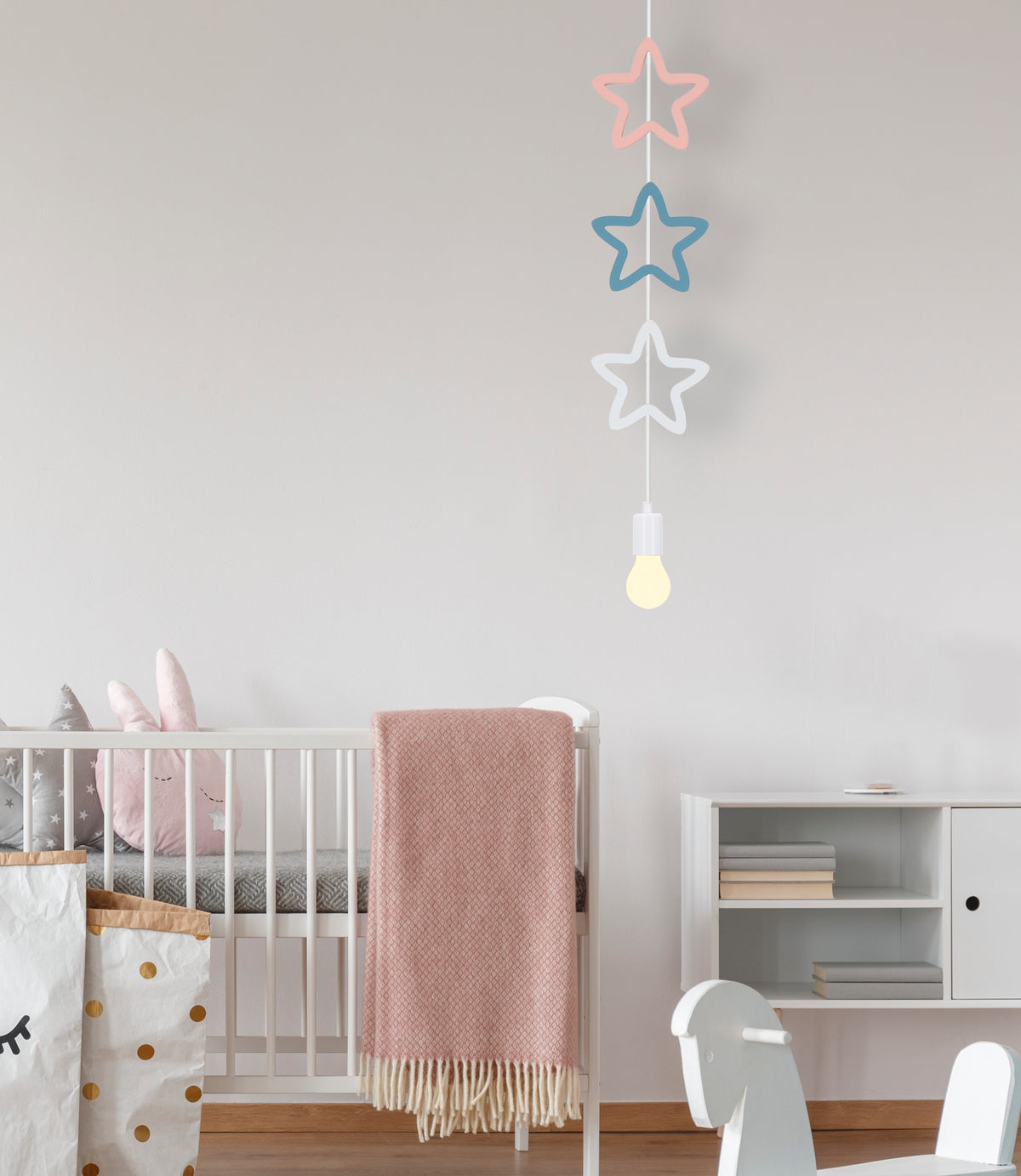 Mise en ambiance chambre d'enfant, suspension étoilée suspendue au-dessus du lit, décor doux.