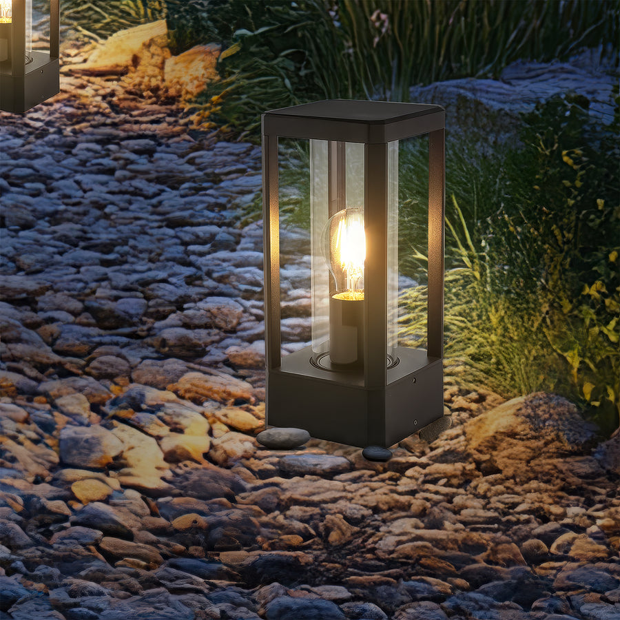 Gros plan nocturne du luminaire allumé, ampoule chaude et reflets sur pierres décoratives.