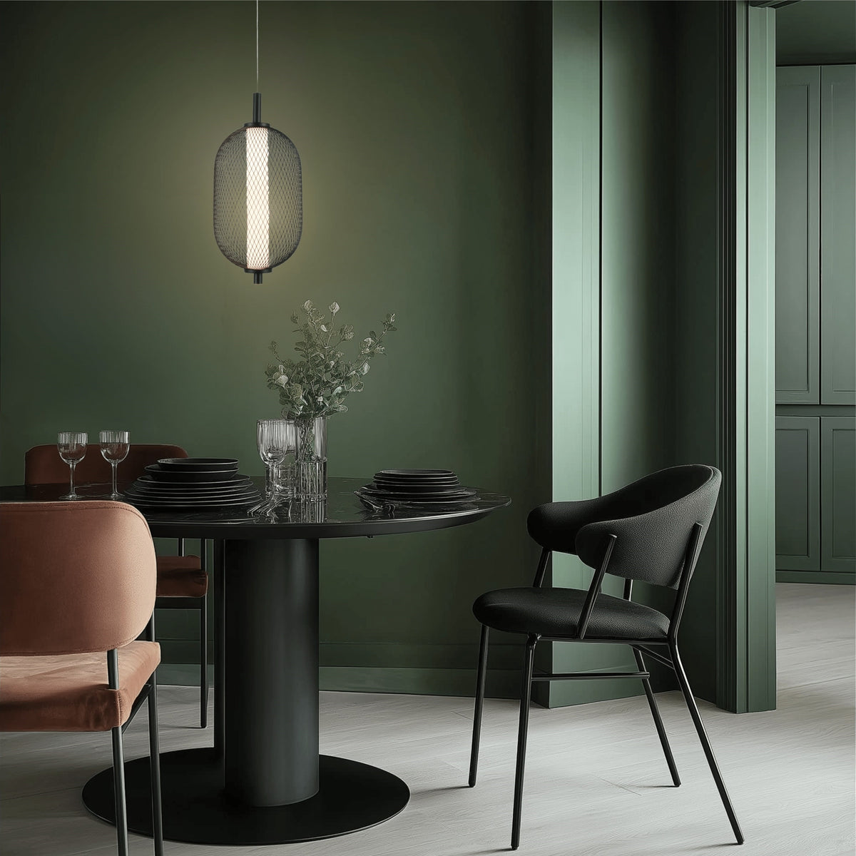 Suspension allumée au-dessus d'une table noire dans une salle à manger verte.
