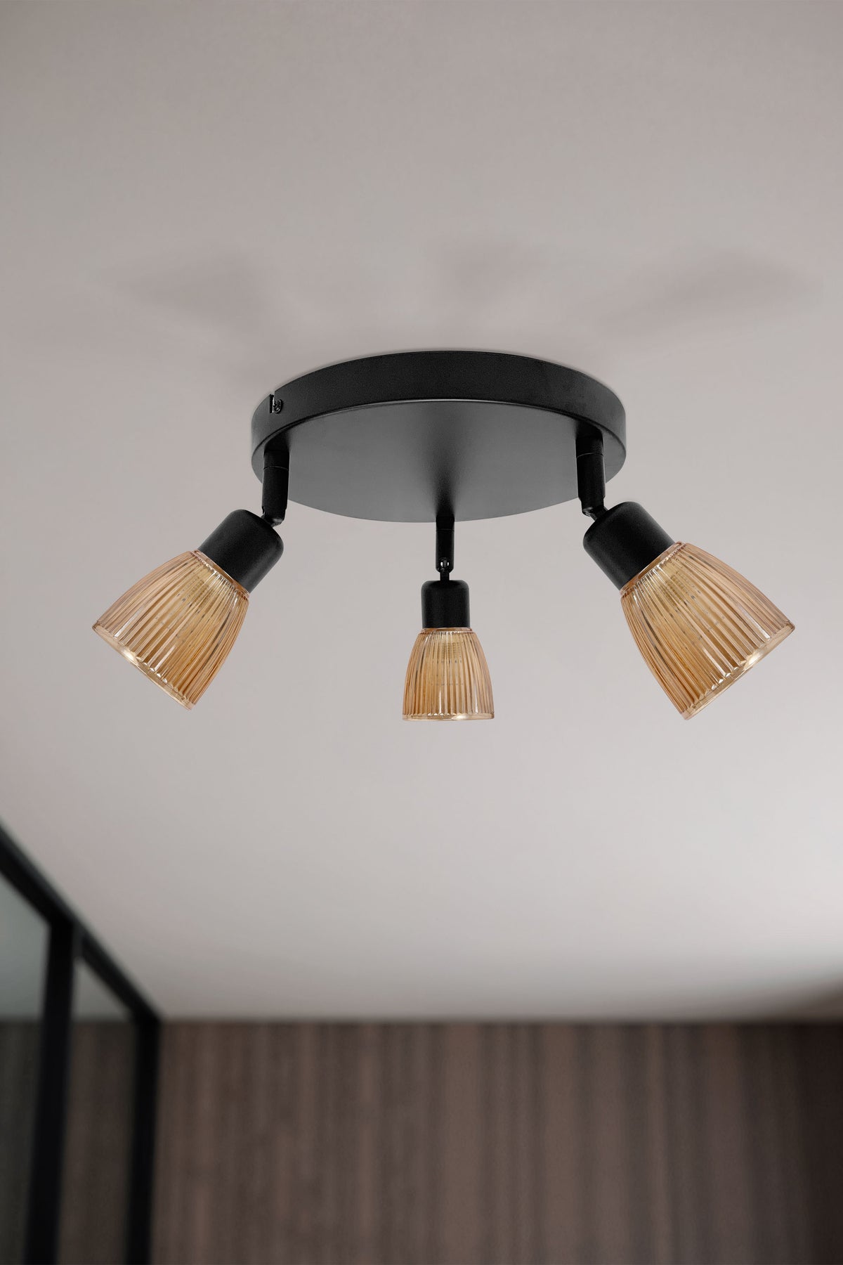 Vue en situation d'un plafonnier trois lumières fixé au plafond, spots orientés vers le bas