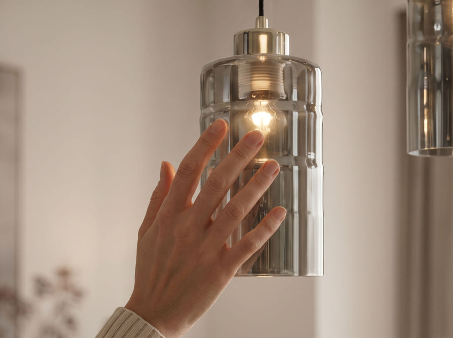 Détail d'une main touchant le verre fumé et l'ampoule allumée