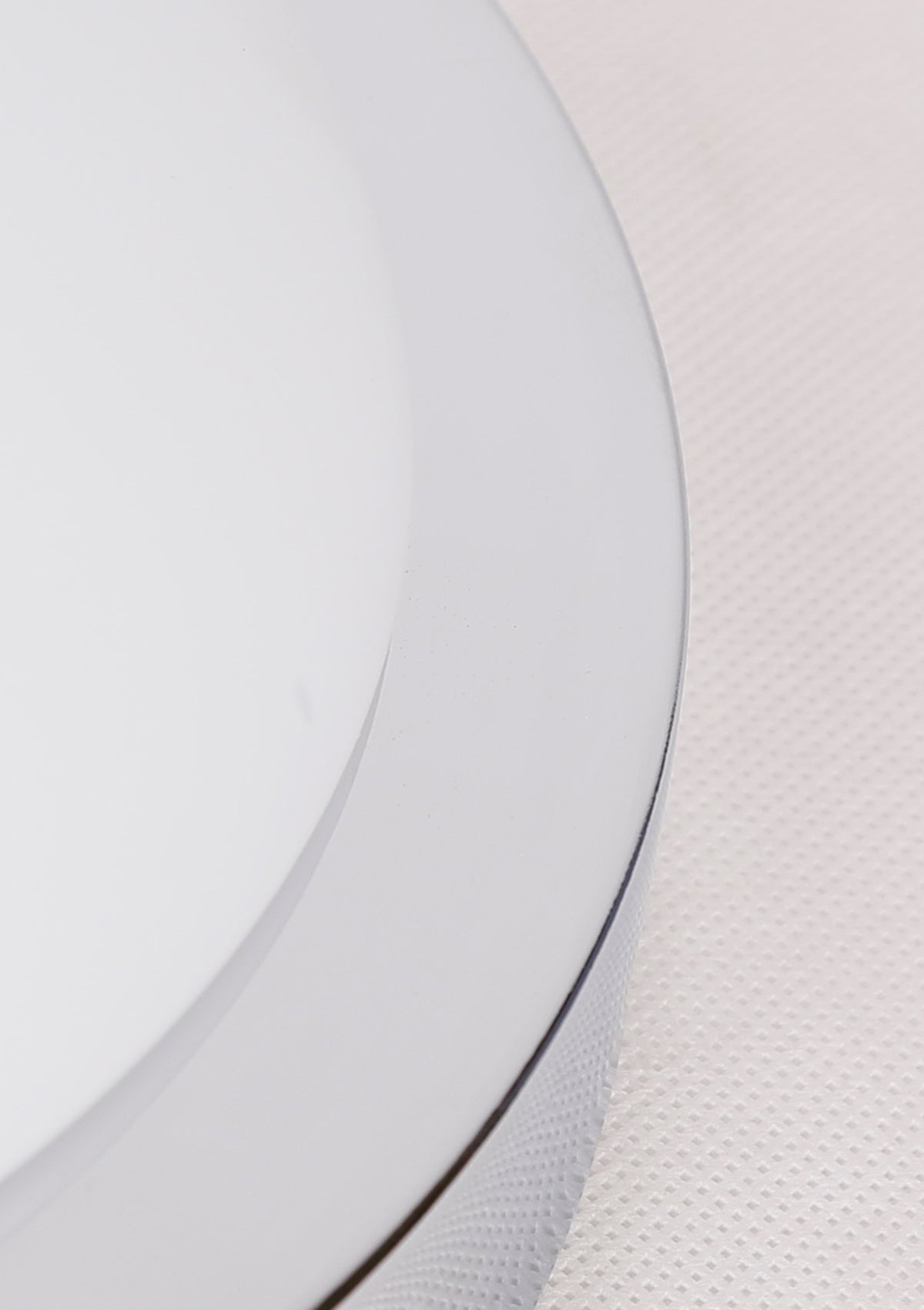 Gros plan sur le bord du diffuseur en verre blanc et son cerclage.