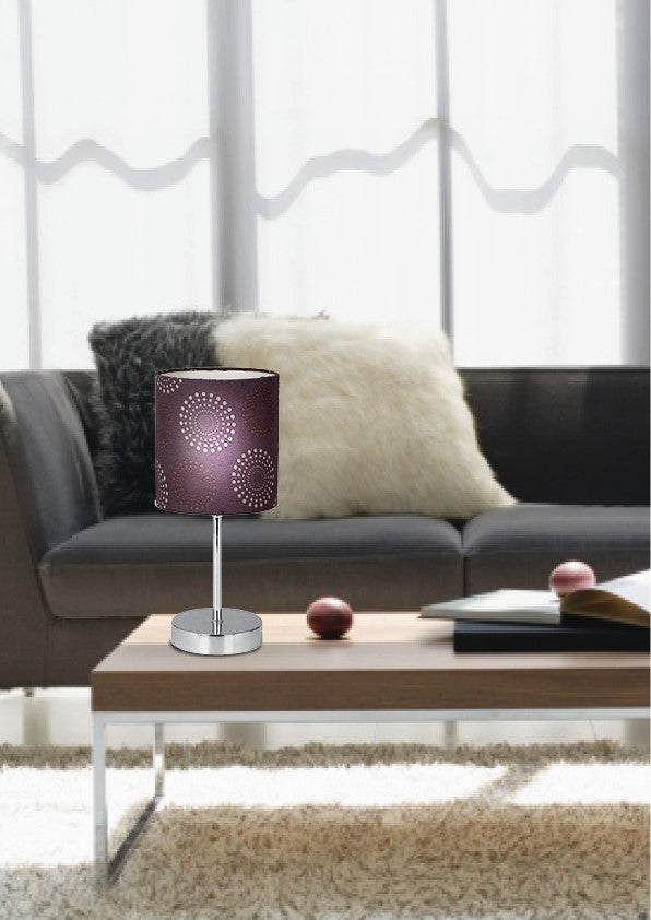 Mise en ambiance salon : lampe posée sur table basse en bois devant un canapé gris.