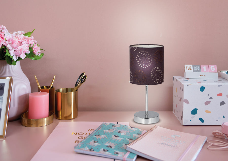 Ambiance bureau rose : lampe allumée près de carnets, bougie et pots à crayons dorés.