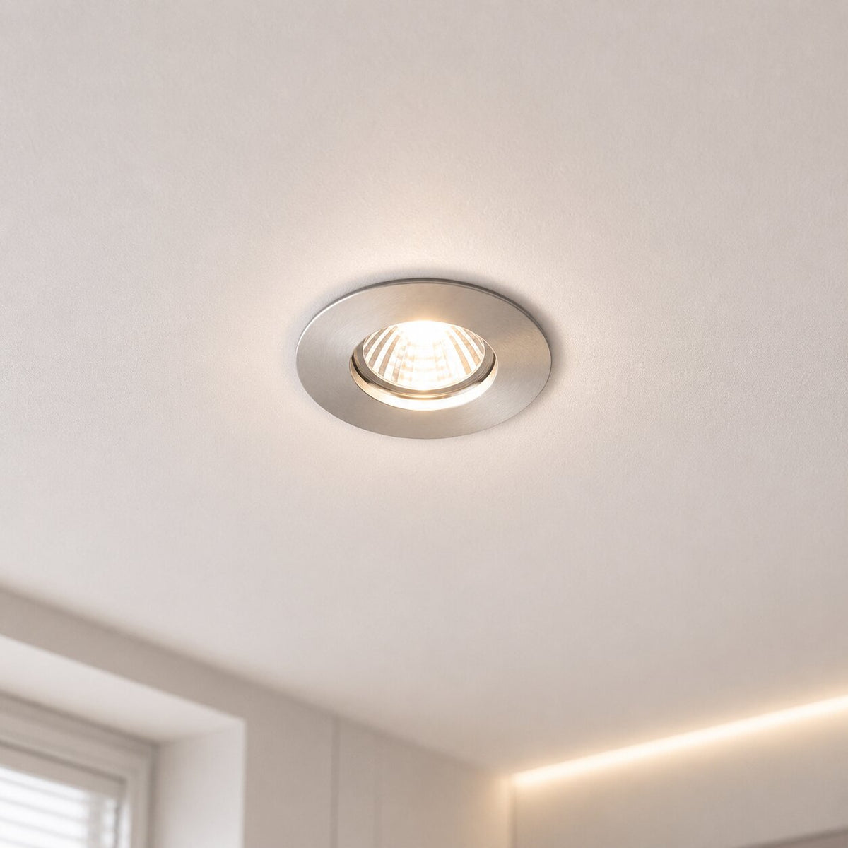 Gros plan d'un spot encastré éclairé dans un plafond blanc, lumière chaude