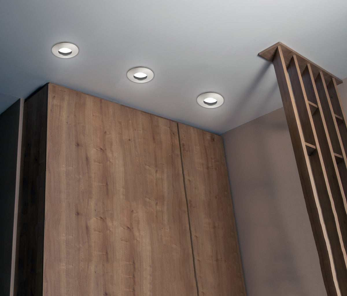 Vue en plongée de spots encastrés alignés sur plafond, ambiance intérieure bois clair