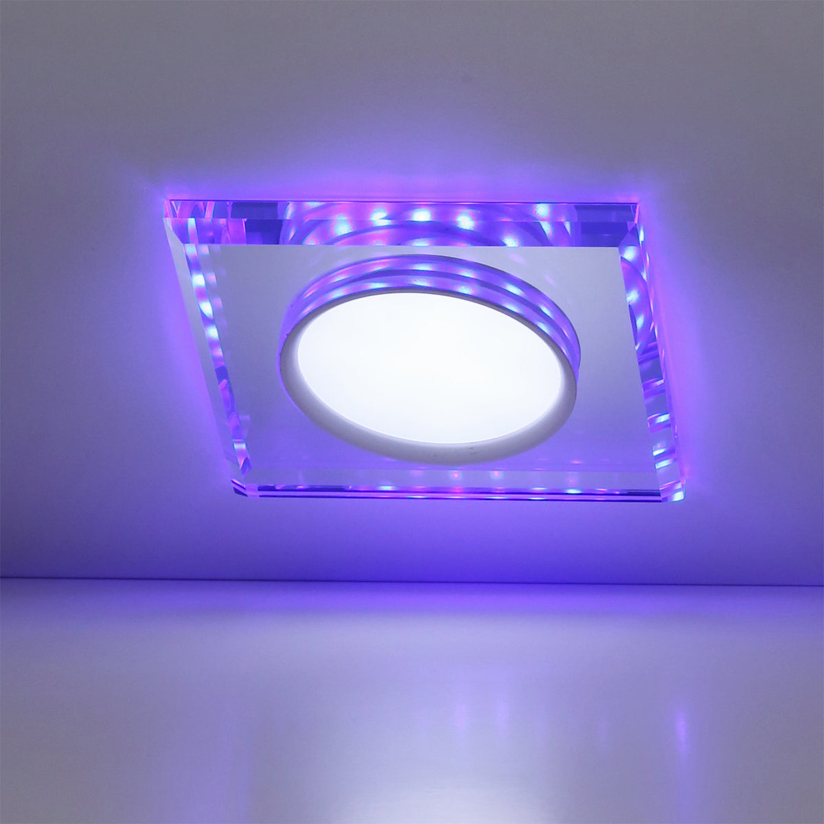 Luminaire allumé de face, éclat violet diffusé sur le plafond blanc