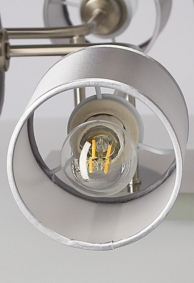 Gros plan sur une ampoule LED à filament visible dans un abat-jour cylindrique.