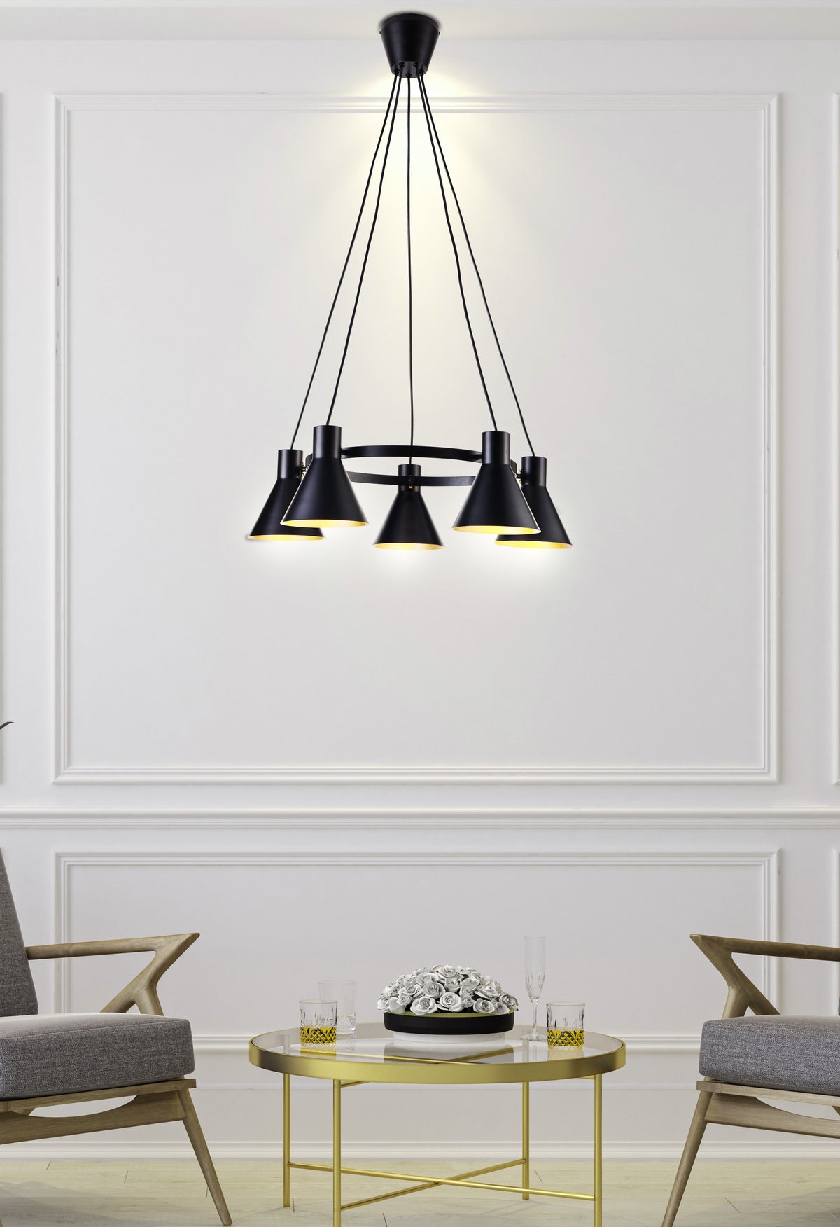 Mise en ambiance salon devant un mur blanc mouluré, suspension éclairée au-dessus de la table basse