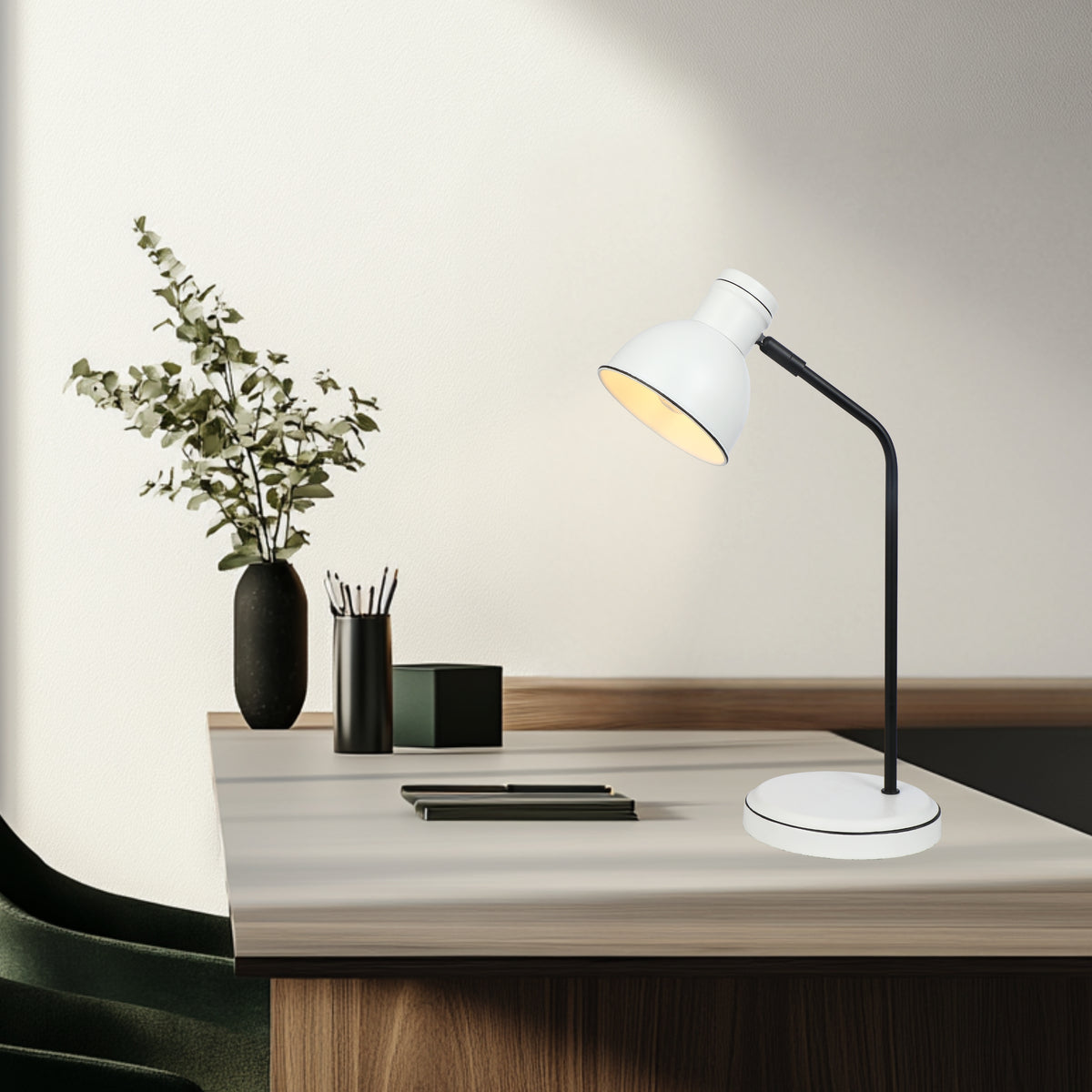 Lampe de bureau posée sur table en bois clair avec plante et accessoires