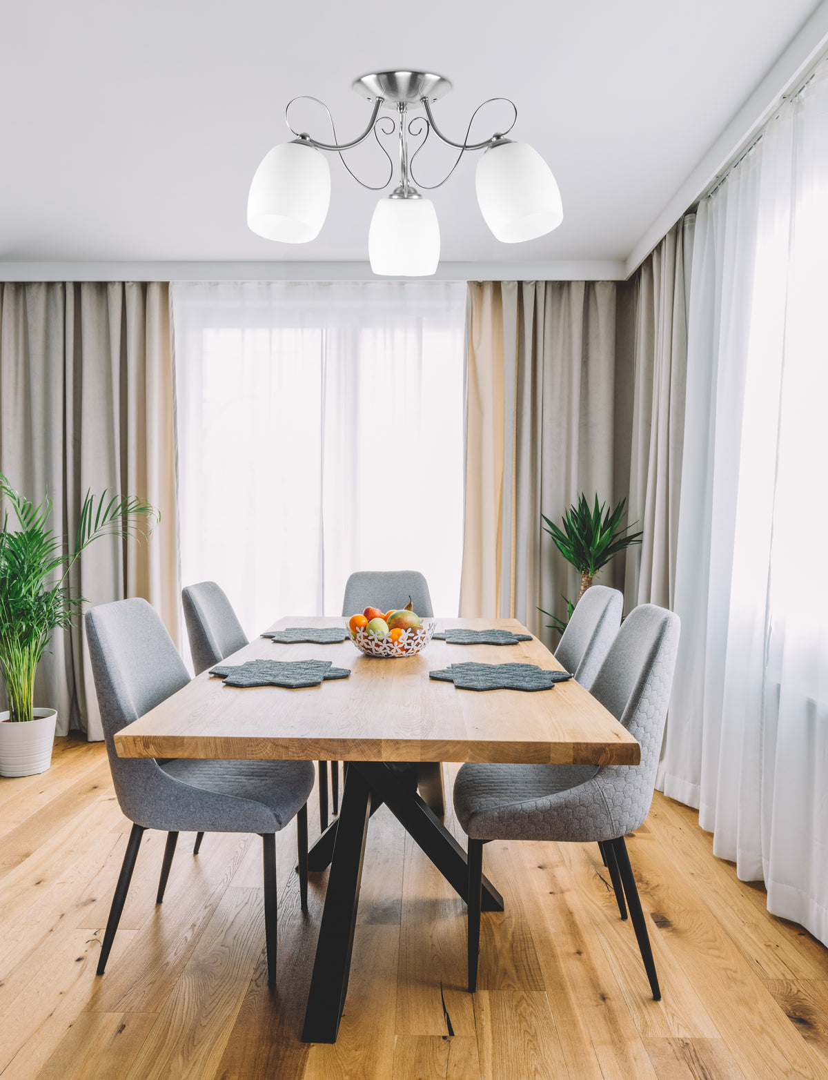 Plafonnier installé au-dessus d'une table à manger en bois clair dans un séjour