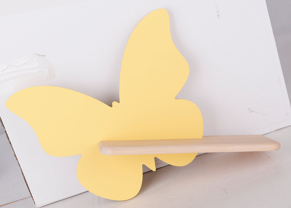 Vue de face du papillon jaune posé contre un carton blanc, étagère bois