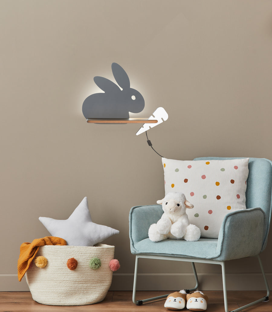 Vue rapprochée de l'applique lapin grise éclairée, halo lumineux diffus sur le mur beige