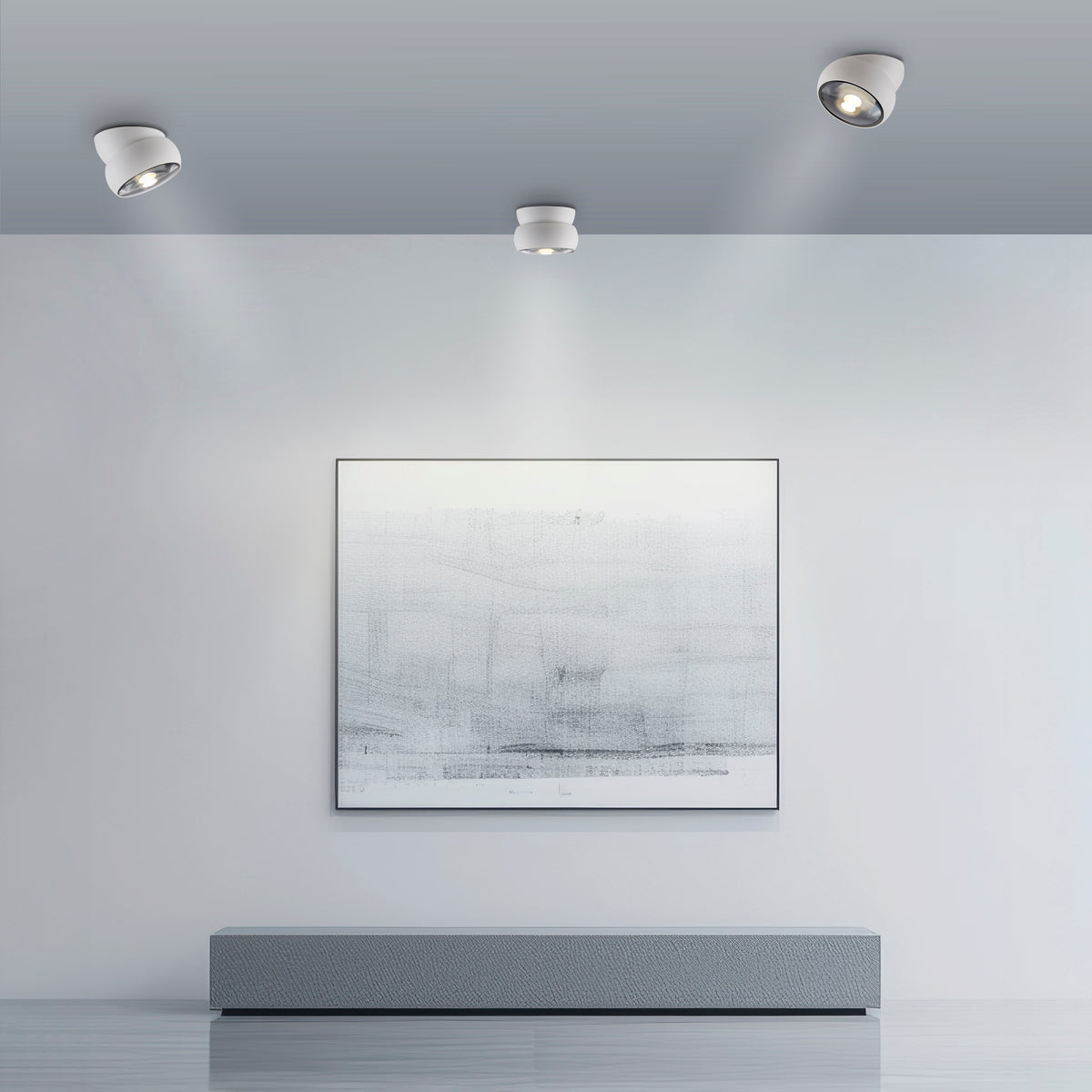Mise en ambiance de trois plafonniers blancs orientés vers un mur gris.