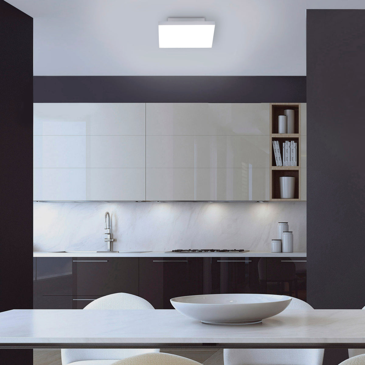 Mise en ambiance au-dessus d’une table de cuisine moderne avec le plafonnier allumé.