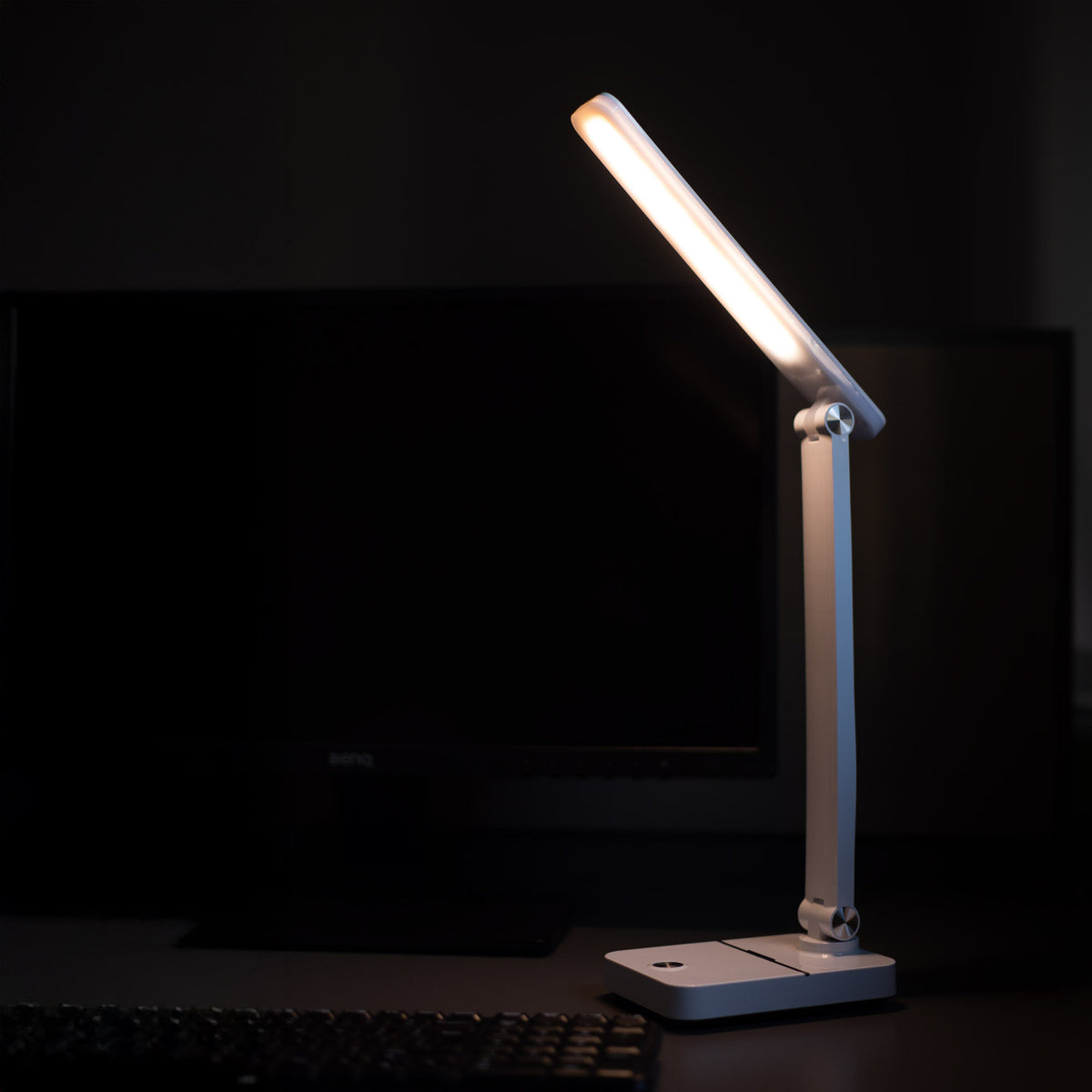 Lampe allumée près d'un écran d'ordinateur et d'un clavier