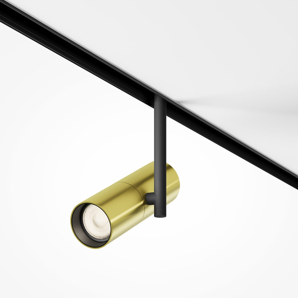 Spot cylindrique doré orienté, fixé sous un rail noir vu de dessous