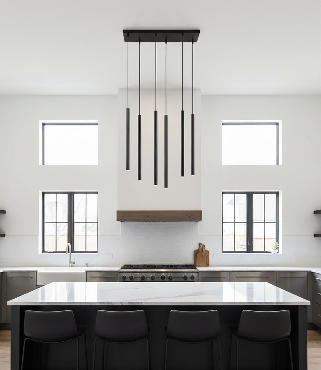 Cuisine blanche avec îlot central et suspension six tubes noirs au-dessus du plan