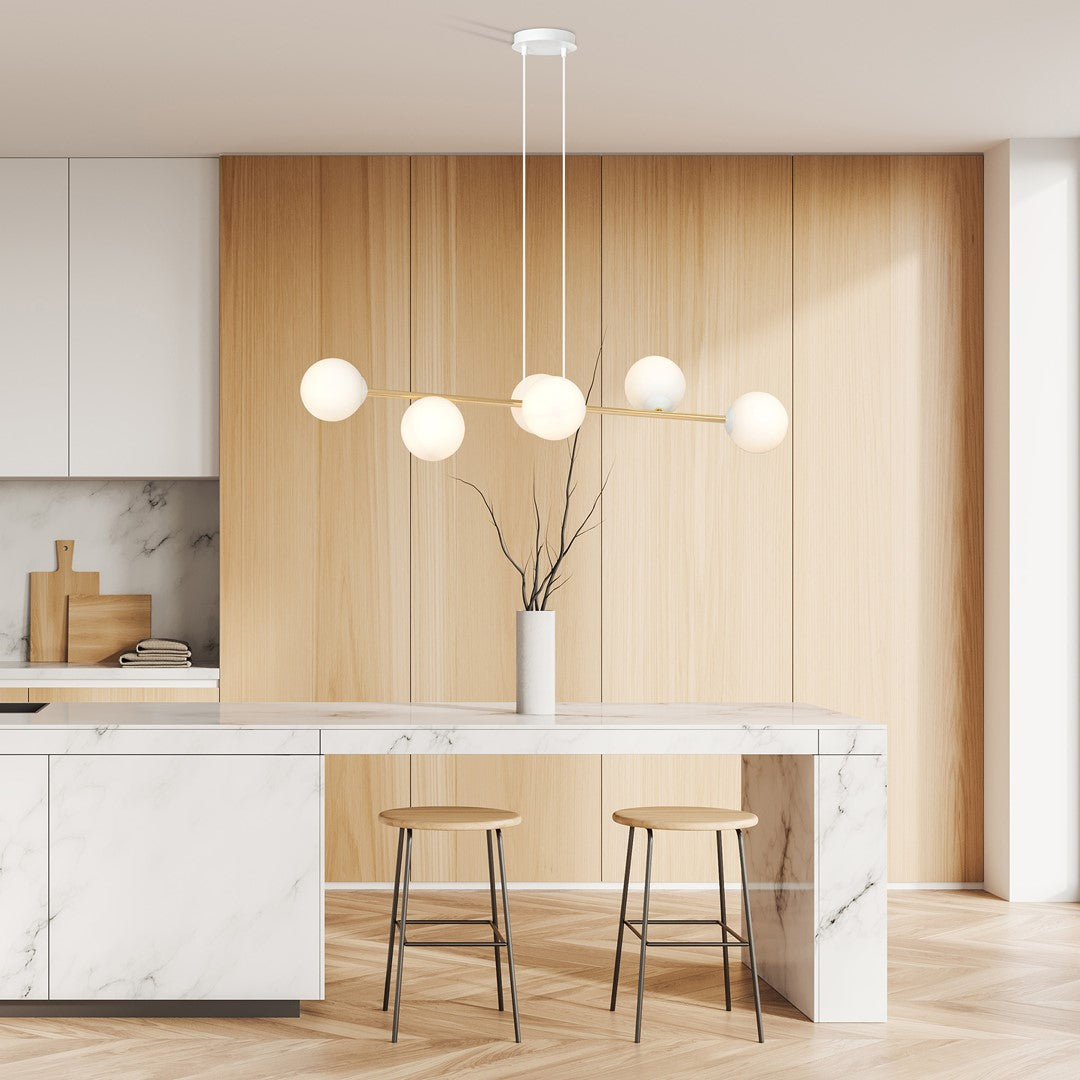 Luminaire suspendu éclairant une cuisine avec plan de travail marbre et mur lambris bois.