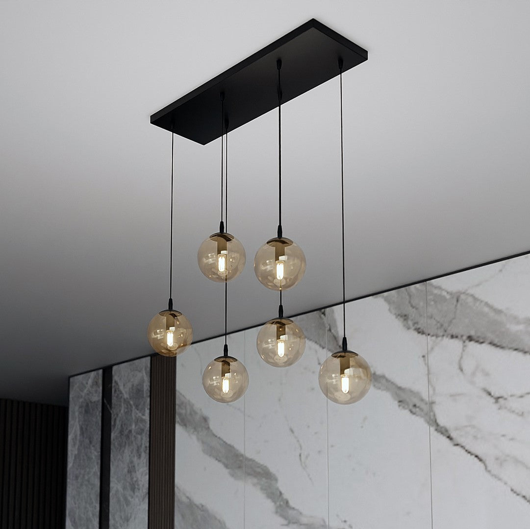 Installation devant un mur de marbre, suspension noire et globes dorés allumés