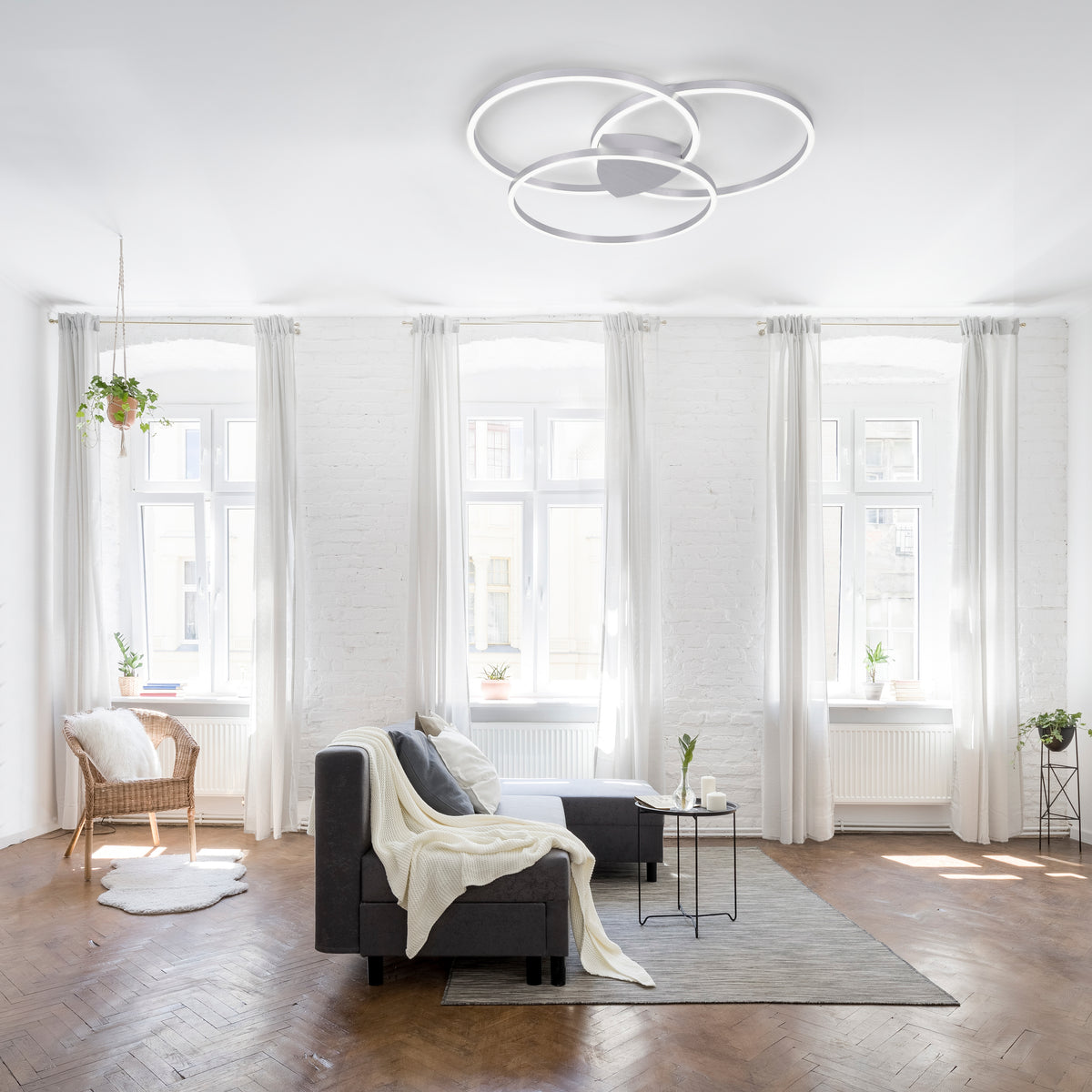 Mise en ambiance dans un salon blanc, plafonnier allumé au plafond au-dessus du canapé.