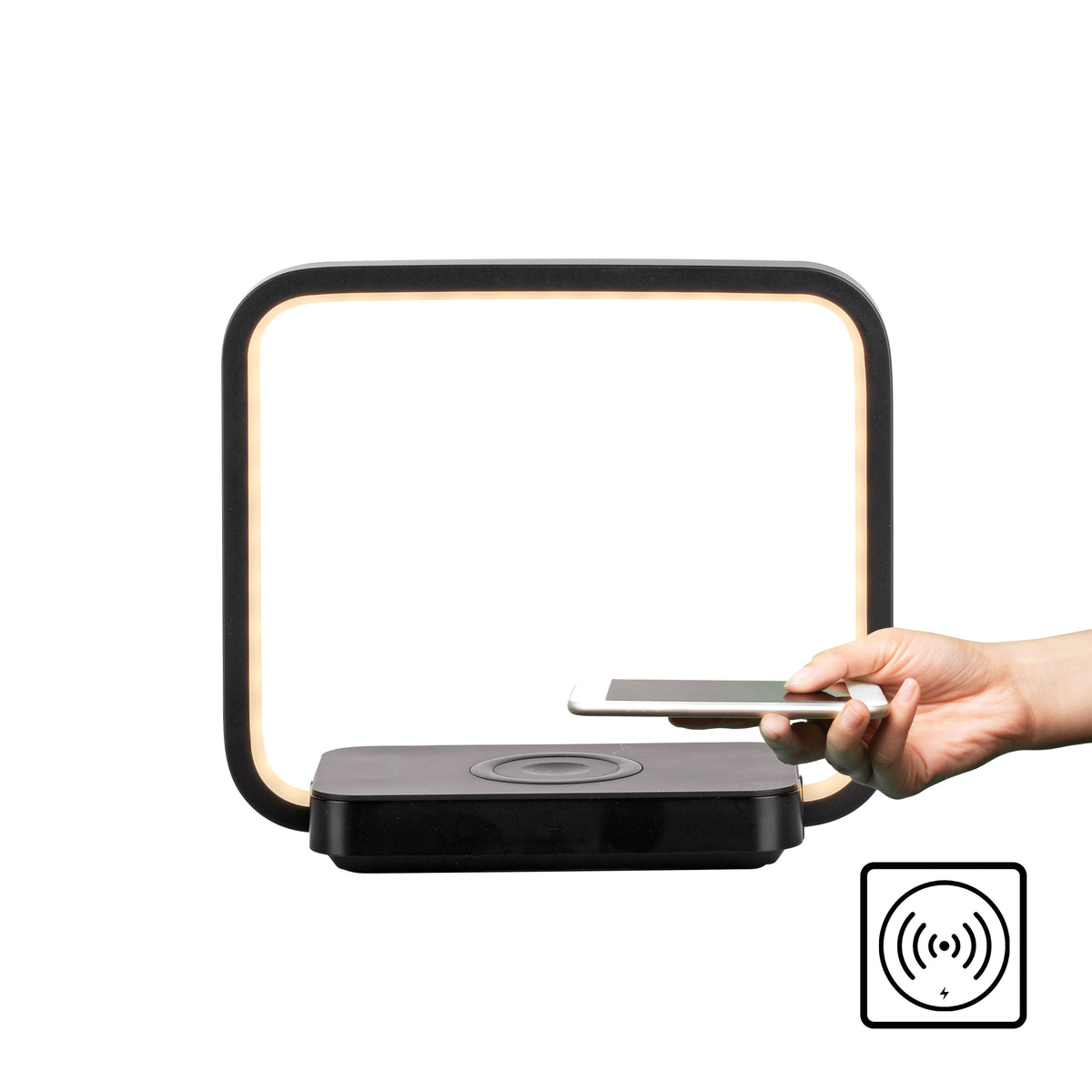 Main approchant un smartphone de la zone de recharge sans fil sur la base.