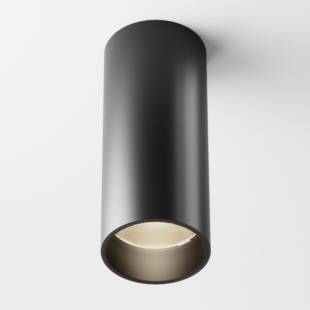 Plafonnier cylindrique noir mat vu de face sur fond clair, spot orientable.