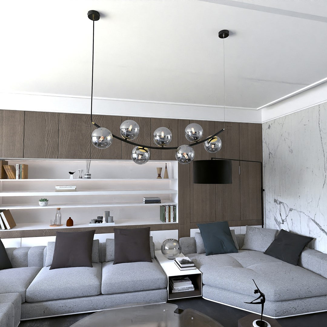 Mise en ambiance dans un salon moderne, la suspension éclaire au-dessus du canapé gris.