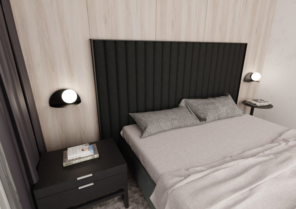 Deux appliques murales éclairent la chambre de chaque côté du grand lit sombre.