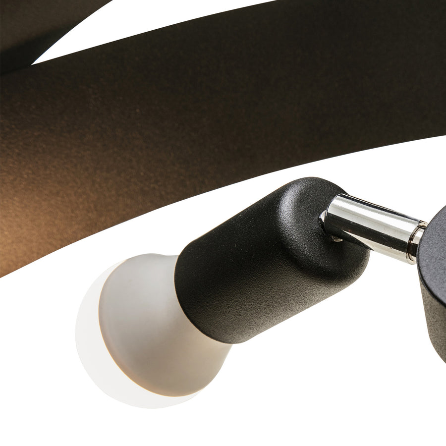 Détail d'une lumière avec support noir, bras chromé et diffuseur blanc.