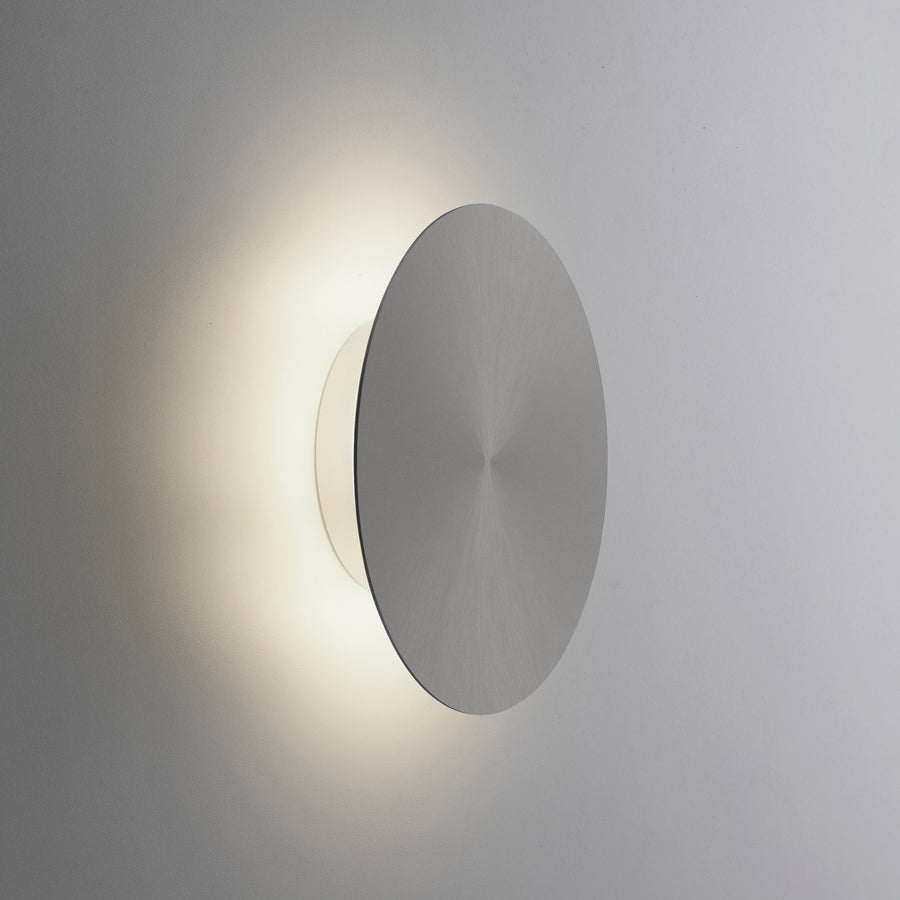 Applique murale allumée sur mur gris diffusant une lumière chaude en biais