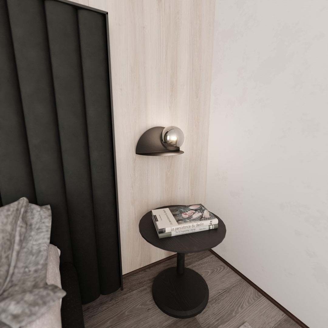 Applique éteinte au-dessus d'une petite table d'appoint ronde noire en coin de chambre