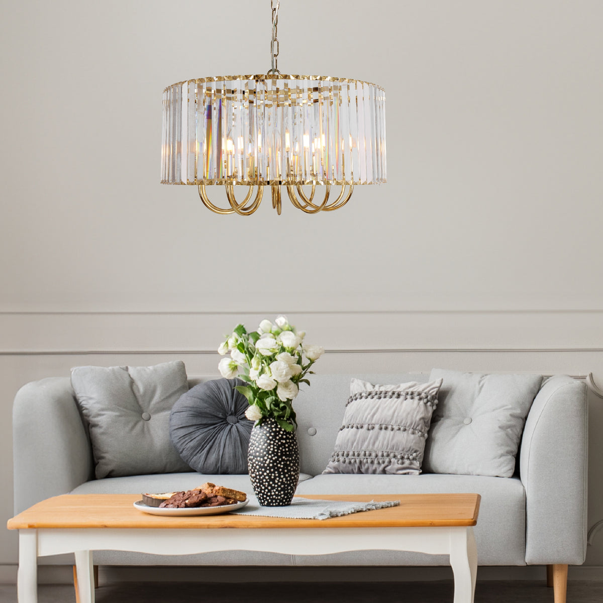 Suspension dorée installée au-dessus d'une table basse devant un canapé gris clair