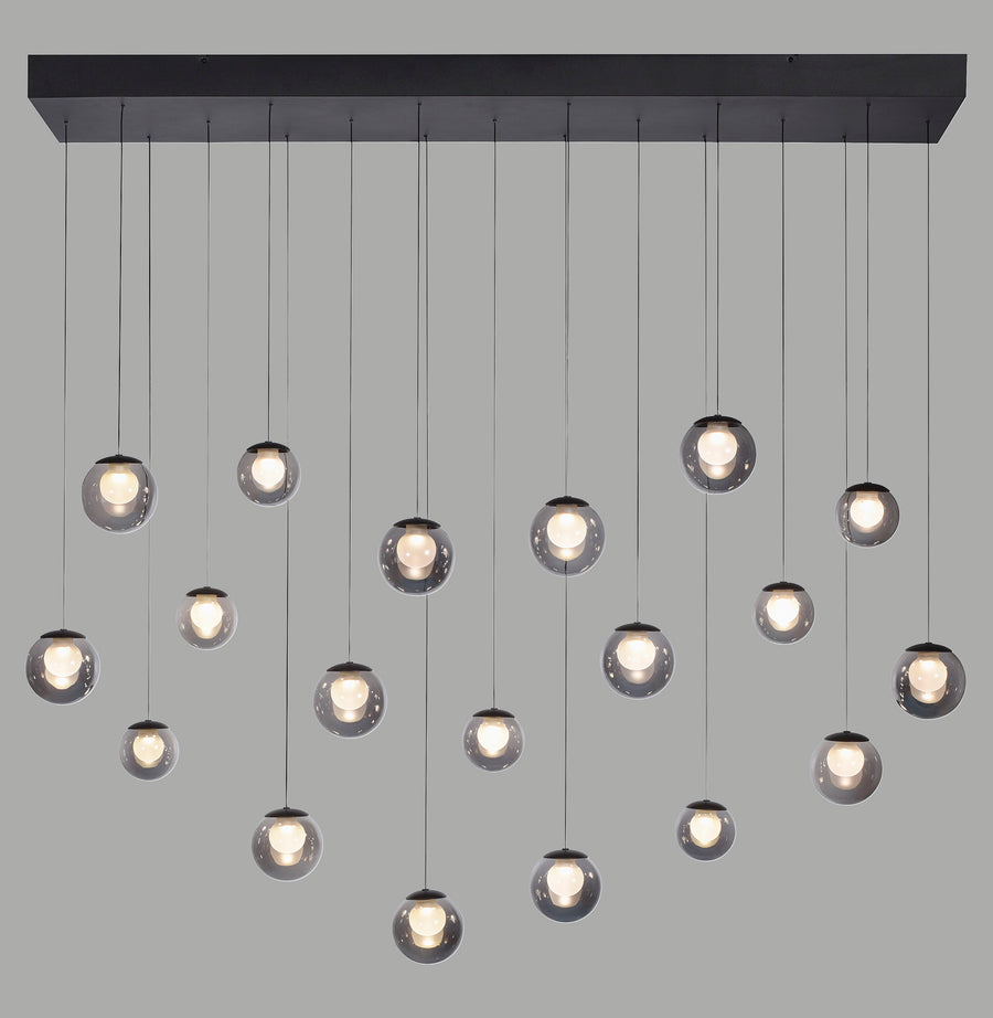 Suspension noire à multiples globes de verre fumé allumés sur fond gris.