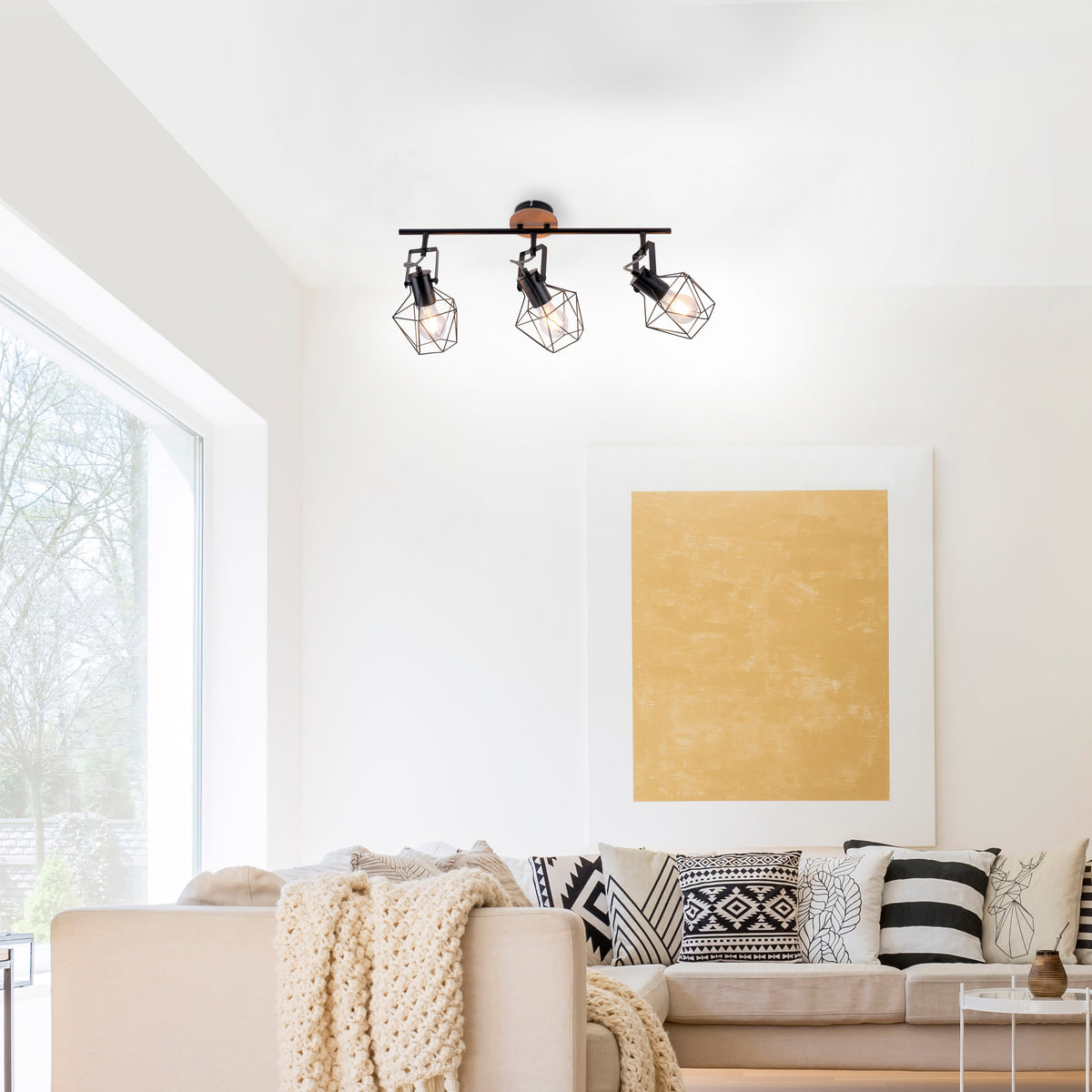 Mise en ambiance dans un salon blanc, luminaire fixé au plafond au-dessus du canapé.