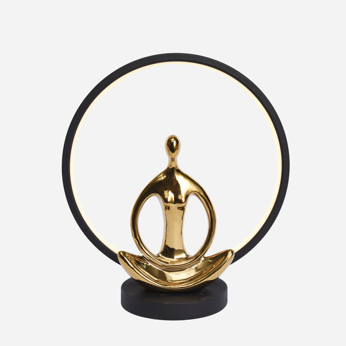 Lampe à poser vue de face, anneau noir lumineux et figurine dorée en posture de yoga