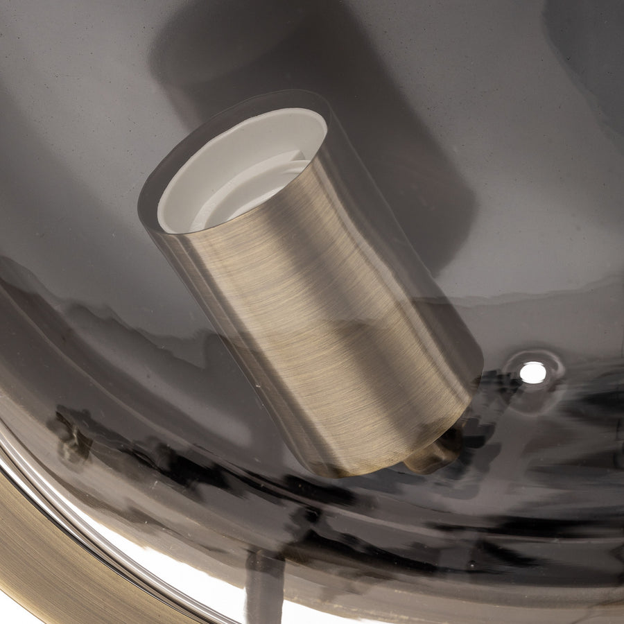 Détail d'une douille cylindrique en laiton sous le verre transparent du luminaire.