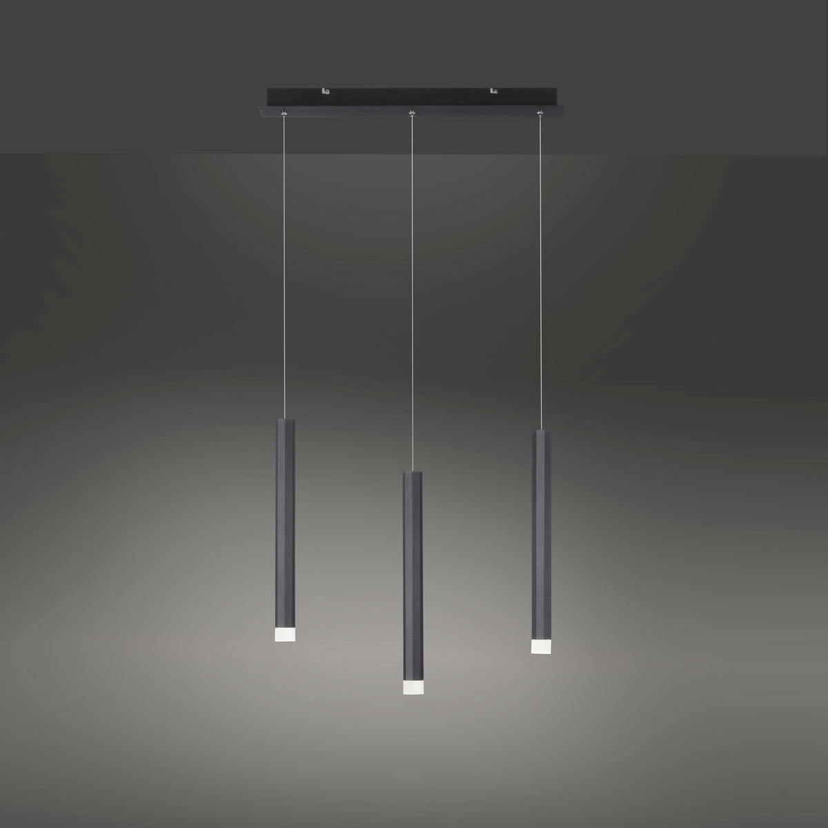 Vue de face sur fond dégradé sombre, les trois tubes noirs laissent échapper une lumière chaude.
