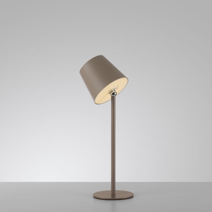 Lampe à poser beige, abat-jour incliné, pied fin et base ronde sur fond clair.